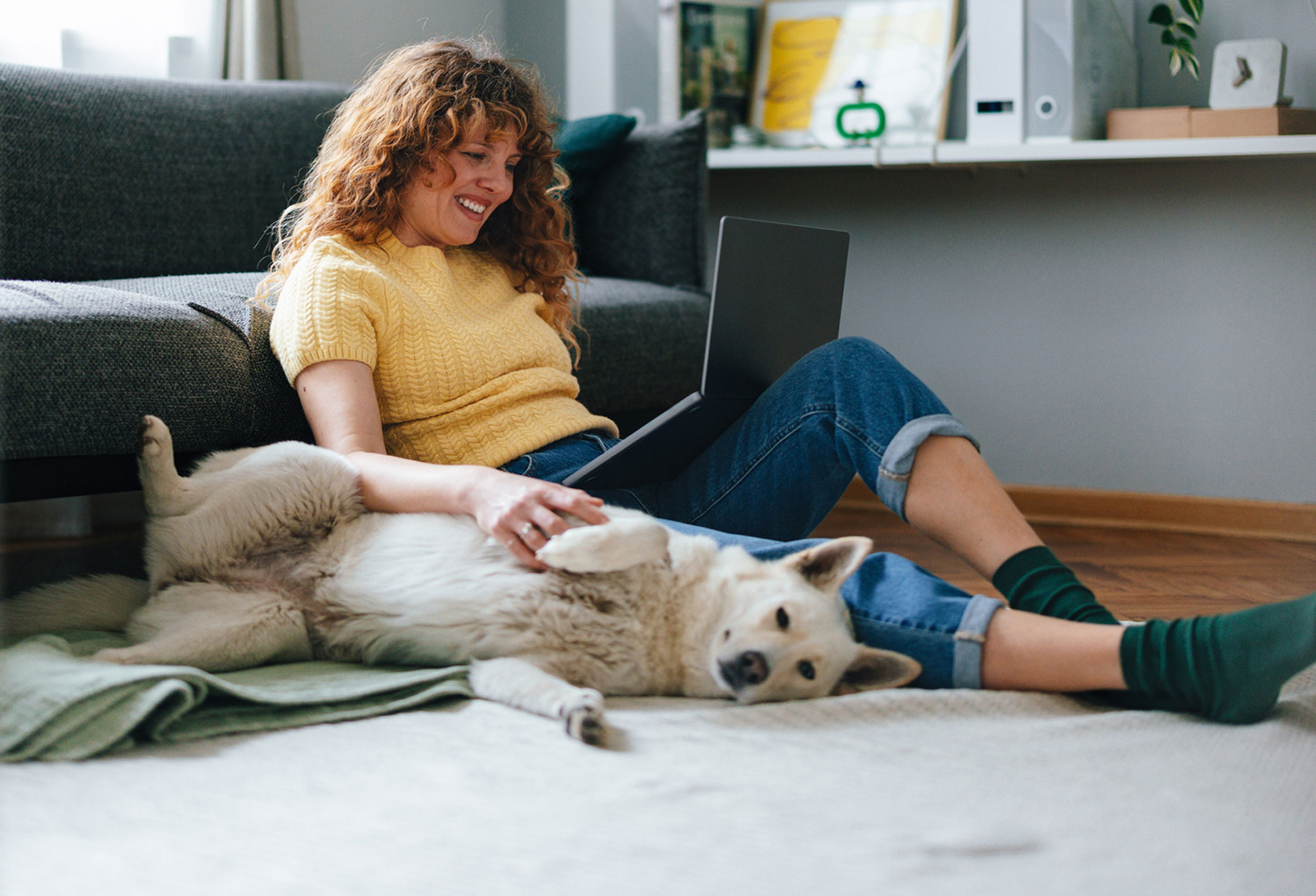 SPS customer relaxing at home with her laptop and her dog