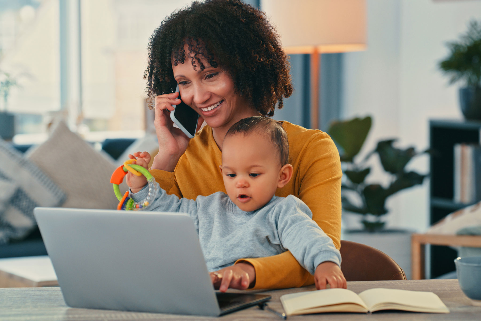 SPS customer on the phone at her laptop while holding her baby